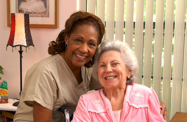 Smiling Care Professional with elderly woman in pink robe