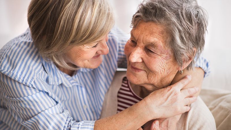 Daughter sitting close with her elderly mother at home