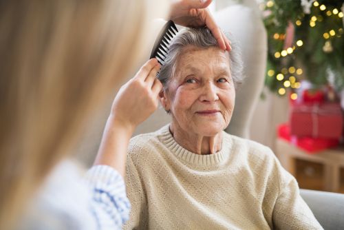 A caregiver helping an older woman with her hair and grooming